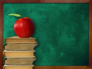 apple on stack of books  against  classroom chalk board