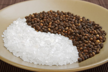 salt crystals and whole black peppercorns in eastern design