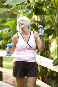 Woman Exercising In Park Walking With Hand Weights