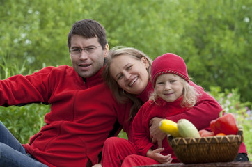 Fototapeta premium Happy family in red picnicked on the grass