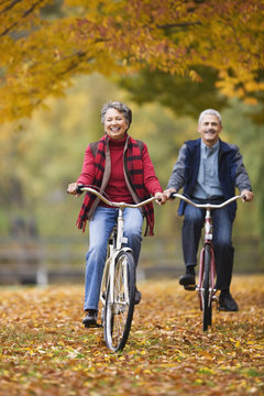 African couple riding bicycles in park in autumn