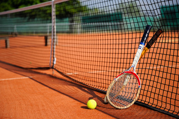 tennis ball, racket and net on the sand court