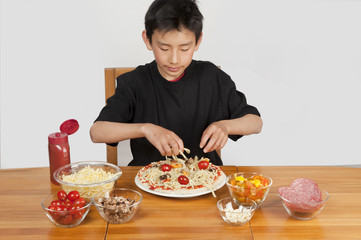 young asian boy making home-made pizza