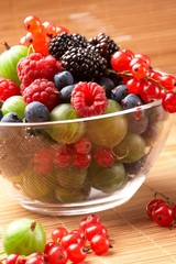 Fruit mix in the glass container, on a table from straw