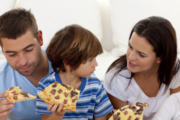 Prents and son eating pizza in living-room