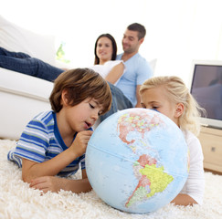 Fototapeta premium Children playing with a terrestrial globe in living-room