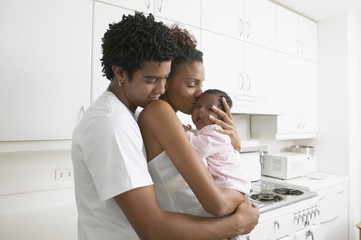 African parents hugging baby in kitchen