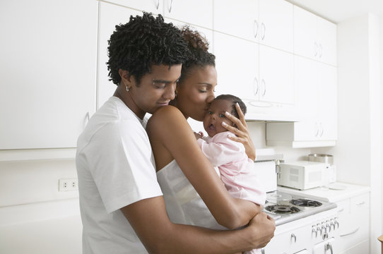 African parents hugging baby in kitchen
