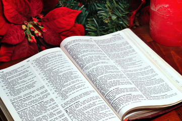 Bible open to the nativity story with poinsettia and candle