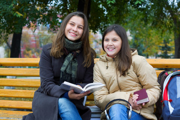 Naklejka premium Two young girls reading in the park.