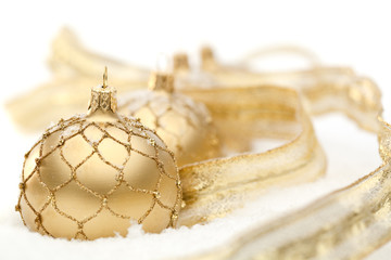 four golden christmas baubles in snow