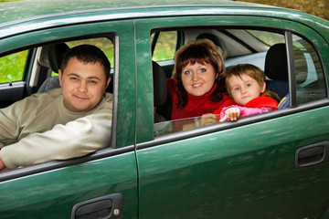 Married couple and  little girl sit in car in park