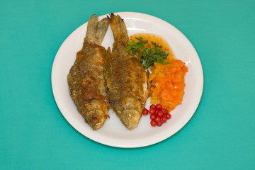 Fried fish in plate on a green background
