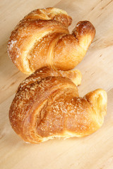 Two croissants over wooden background