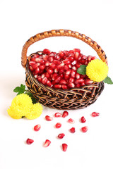 Ripe grains of a pomegranate and flowers in a basket.