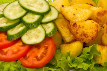 Fried potatoes with fresh cucumbers and tomatoes on studio white