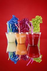 Colorful kid's party smoothies and gift bags on red
