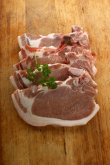 organic raw pork chops on a timber board