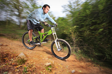 Fototapeta na wymiar A young man riding a mountain bike downhill style