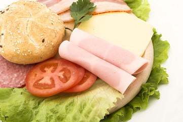 Different type of salami, ham and vegetables on wooden board
