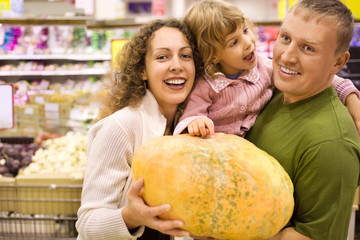 Fototapeta premium family with little girl buy pumpkin in supermarket