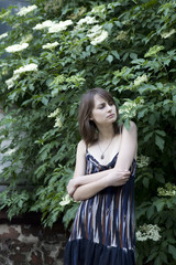 young pensive woman standing at bush