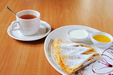 Tea and pancakes  with powdered sugar