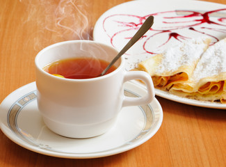 Tea and pancakes  with powdered sugar