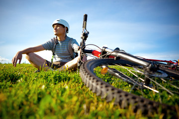 Mountain biker resting in a grass.