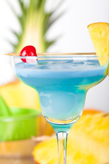Blue alcohol cocktail with pineapple and cherry