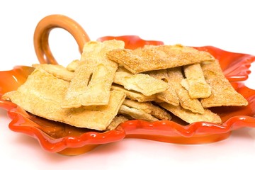 Khvorost with sugar on a plate in the form of autumn leaf