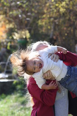 bébé fille hilare soulevée par sa maman