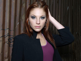 Fototapeta premium Attractive female fashion model with red hair in a dark alley