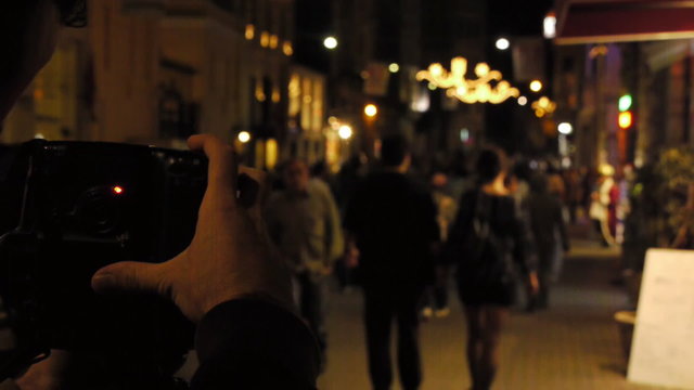 A photographer takes picture of a crowded street at night