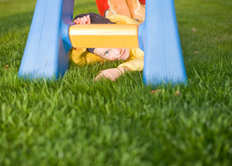 Little smiling positive child lay on grass near slide