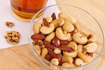 Salty and crunchy mixed nuts with a tall glass of lager beer