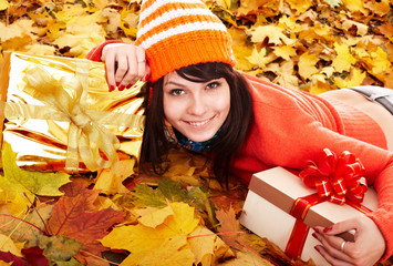 Girl in autumn orange hat on leaf group with group gift box.