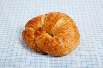 A croissant on a blue gingham tablecloth