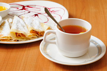 Tea and pancakes  with powdered sugar