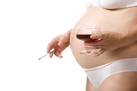 A close-up image of a pregnant woman holding a wine glass in one hand and a cigarette in the other, highlighting pregnancy health concerns.