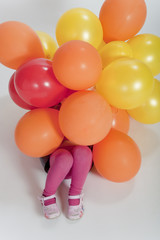 Fototapeta na wymiar little girl covered in colorful balloons
