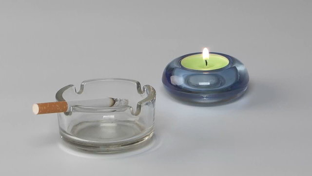 Smouldering cigarette in a transparent ash-tray.