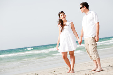 Fototapeta na wymiar Young couple holding hands and walking on the beach