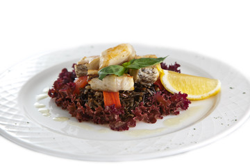 Plate with meal. Fish, wild rice, an orange, lemon, sauce