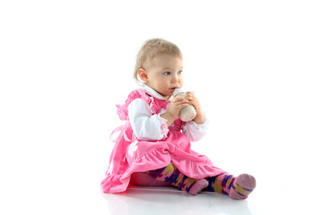 Pretty baby girl is drinking milk in a bottle isolated