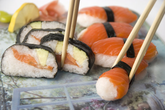 Sushi with chopsticks against white background.