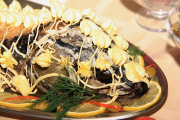 roasted sturgeon decorated with lemons, seaproducts, vegetableso