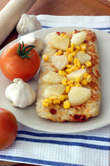 Fototapeta na wymiar stone oven baked pizza with corn, tomato and garlic