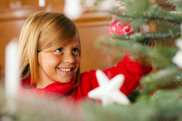 Kind schmückt Weihnachtsbaum