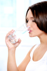 Beautiful girl drinks pure water from a glass